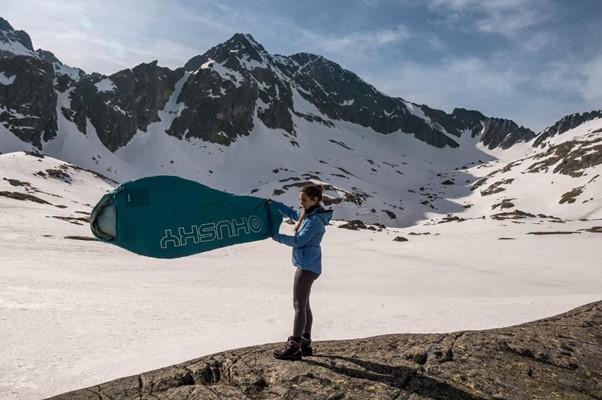 Vyrážíš na vysokohorskou expedici? Víme, co s sebou. Dívka držící spacák